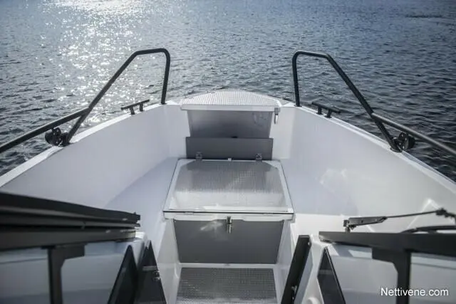 View from the bow of a modern boat showcasing the deck, storage compartment, and shimmering water in the background.